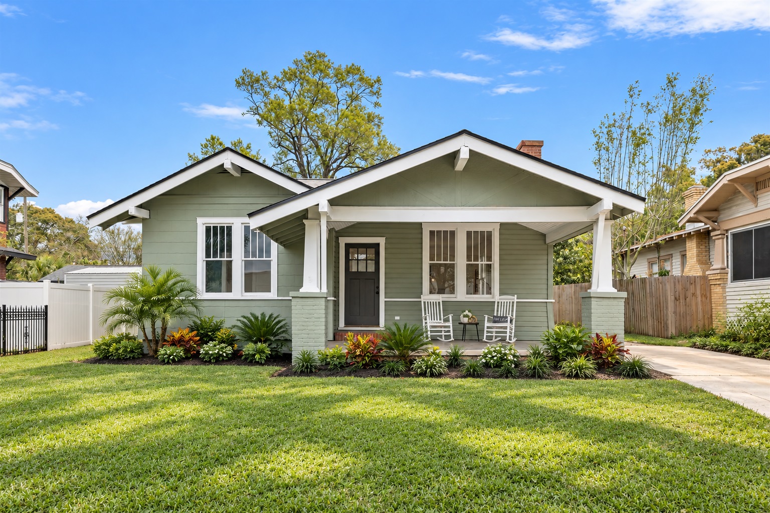Green and gray bungalow home with a covered front porch